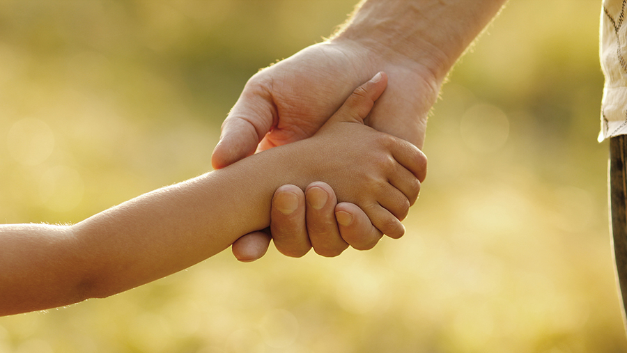 the parent holds the hand of a small child